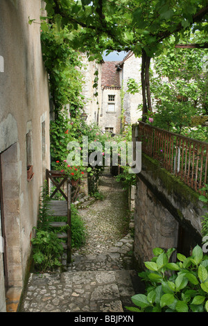 Rue étroite et verdoyante dans le village de Saint-Cirq-Lapopie à côté de la rivière Lot, Midi Pyrénées, France Banque D'Images