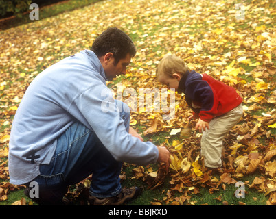 Le père avec son fils jouant avec les feuilles d'automne Banque D'Images
