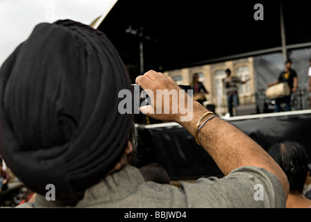 Homme sikh taking photograph at Birmingham artsfest concert 2008 Banque D'Images