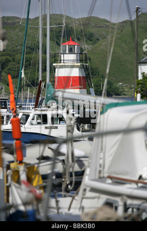 Crinan Canal, l'Écosse. Bateaux voile loisirs amarré dans le port de Crinan avec l'entrée du port phare en arrière-plan. Banque D'Images