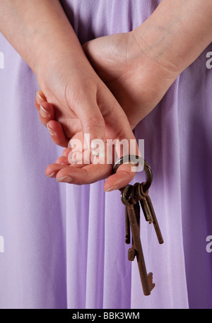 Femme en attente avec old rusty keys se cachant dans ses mains Banque D'Images