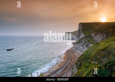 Coucher de soleil au-dessus de Durdle Door vers je Bat s trou avec le Taureau rock sur la gauche Banque D'Images