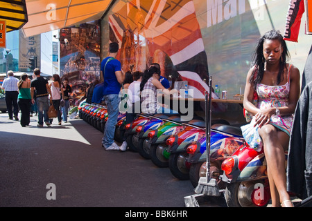 Camden Lock Village Market , jolie fille noire d'adolescent est assis sur la nouveauté ou d'un scooter Lambretta dos utilisés comme sièges pour les stands de nourriture Banque D'Images