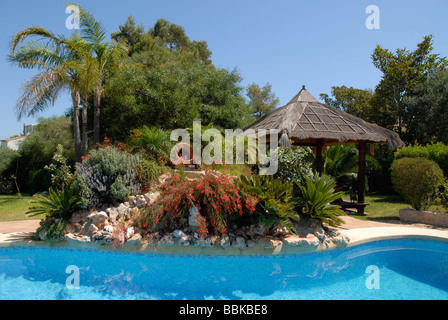 Piscine avec rocaille et cabane dans un jardin balinais, Javea / Xabia, Province d'Alicante, Communauté Valencienne, Espagne Banque D'Images
