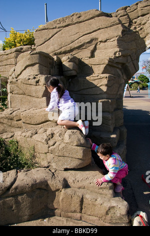 Deux demi-Thai pour escalader un mur artificiel en plein soleil près de la promenade à Skegness Banque D'Images