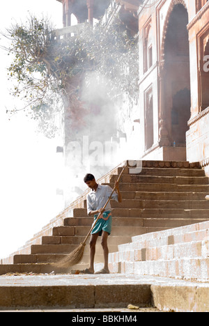 L'homme de basse caste balayer une echelle ghat de Varanasi, Inde. Banque D'Images