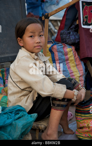 Hmoung siège enfant sur son échoppe de marché à Luang Prabang au Laos Banque D'Images