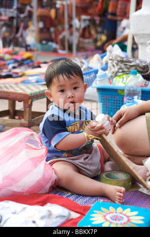 Un petit garçon joue sur sa mère au marché de nuit de Luang Prabang au Laos Banque D'Images