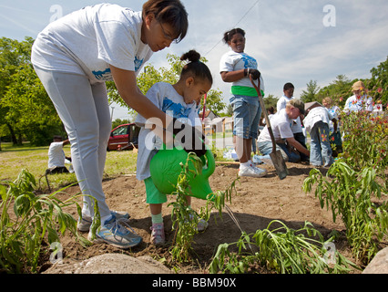 Détroit, Michigan Une mère aide son jeune enfant planté des plantes de l'eau par des bénévoles dans le parc de la Rouge dans le cadre d'un nettoyage du parc Banque D'Images