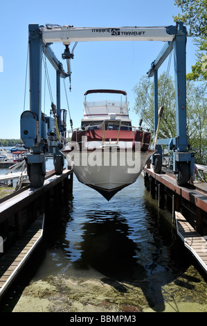 Luxury cabin cruiser dans l'élingue de chargement, étant descendu dans l'eau. Banque D'Images