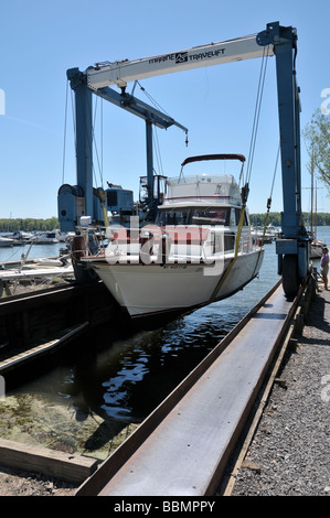 Luxury cabin cruiser dans l'élingue de chargement, étant descendu dans l'eau. Banque D'Images