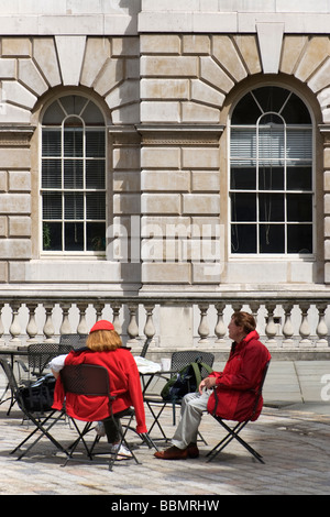 Un couple d'âge moyen portant des vêtements rouges, assis à une table dans la cour à Somerset House à Londres UK Banque D'Images