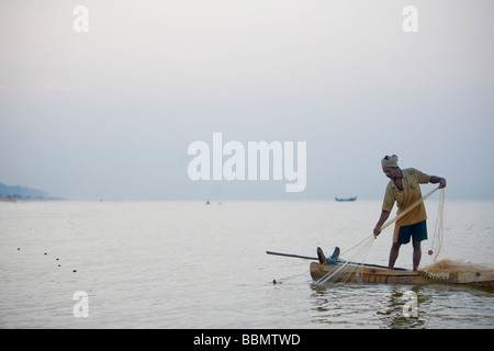 Pêcheur de subsistance des Indiens tirant dans ses filets de bateau en bois faits à la main près de la rive. Banque D'Images