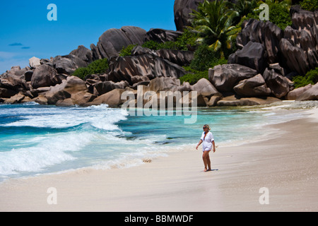 Femme d'exécution sur la plage de Grand Anse, avec les roches de granit typique de la digue, de l'Océan Indien, l'île de La Digue, Seychelles Banque D'Images