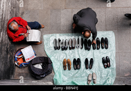 Mann vend des chaussures dans la rue, un client atteint pour une chaussure, vue de dessus, Istanbul, Turquie Banque D'Images