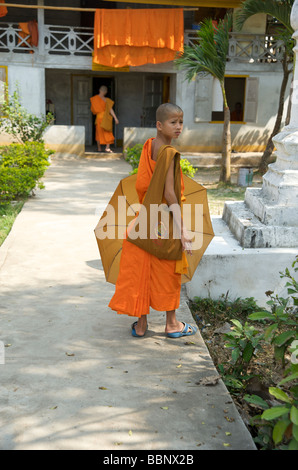 Un jeune moine bouddhiste novice lao sur le chemin du retour vers son logement donne sur son épaule Banque D'Images