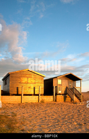 Cabines de plage à Walberswick illuminée par la lumière d'été chaude soirée sur la côte du Suffolk. Banque D'Images