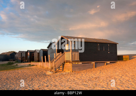 Cabines de plage à Walberswick illuminée par la lumière d'été chaude soirée sur la côte du Suffolk. Banque D'Images