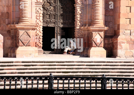 L'homme situé en face de la porte de la cathédrale de Zacatecas au Mexique une petite ville baroque colonial building façade en pierre rouge Banque D'Images