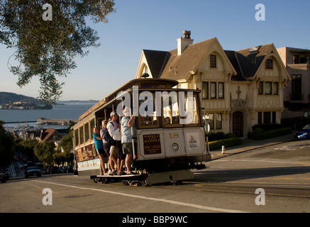 Vue Classique d'un téléphérique jusqu'ascendant Powell Street, San Francisco, Alcatraz avec en arrière-plan. Le téléphérique est suivie d'une Ford Mustang. Banque D'Images