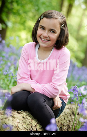 Jeune fille assise dans un bois plein de bluebells Banque D'Images