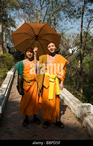 Deux moines novices sur le chemin jusqu'à la colline de Phou Si temple de Luang Prabang se protéger du soleil avec un parapluie Banque D'Images