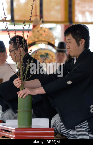Un homme démontrant l'art de l'ikebana, ou l'arrangement de fleurs à l'aide de bourgeons de printemps et d'un vase en bambou à Kyoto, au Japon. Banque D'Images