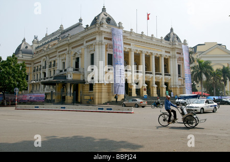 Un pilote cyclo peddles passé l'opéra dans le nord du Vietnam Hanoi Banque D'Images