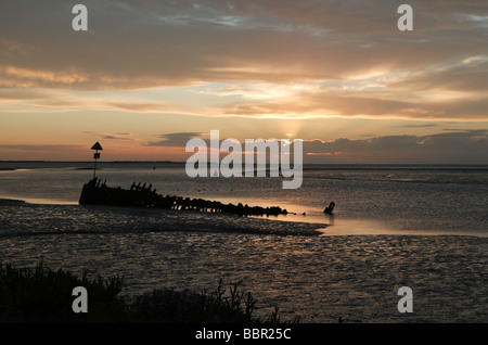 Here Comes the sun. Tôt le matin sur la côte du Kent, avec un bateau abandonné sur la rive Banque D'Images