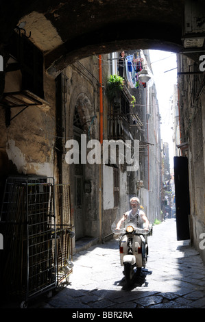 Un scooter rider dans les petites rues de Naples, Italie Banque D'Images