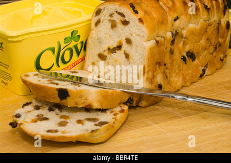 Les fruits tranchés un couteau à pain et un pot de beurre sur une planche à découper en bois Banque D'Images