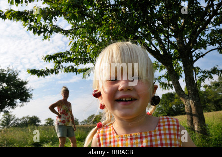 Stock photo d'une fillette de 3 ans la cueillette des cerises avec sa maman elle porte des cerises pour les boucles Banque D'Images