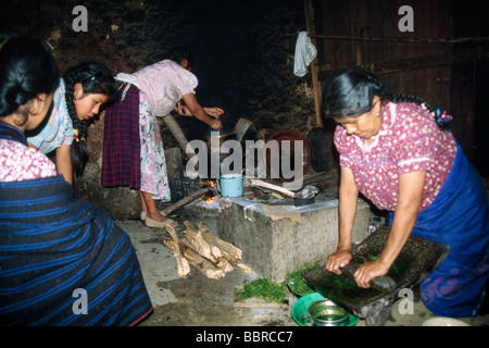 Famille autochtone préparant un repas dans leur cuisine traditionnelle, au Mexique. Outil pour pierre à affûter Metate. Banque D'Images