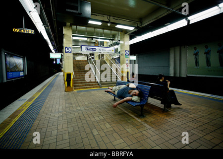 Une épave ou sans-abri endormi sur un siège dans une station de métro Banque D'Images