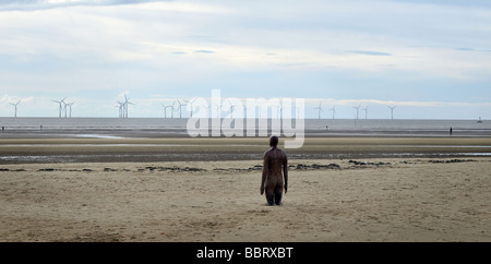 La figure de fer (partie d'Antony Gormley a une autre place) avec des éoliennes. Crosby Beach, Liverpool, Merseyside, Royaume-Uni Banque D'Images