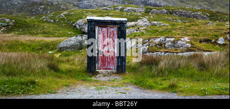 Tin à distance hutte avec une porte en bois rouge vieilli, près de Tarbert, Isle of Harris, Hébrides extérieures, en Écosse Banque D'Images