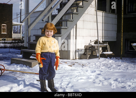 Trois ans joue dans la neige à l'extérieur de la maison canadienne 1956 Banque D'Images