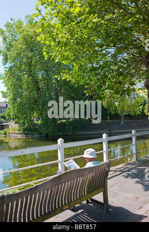 Man relaxing with newspaper assis à côté de la rivière Avon à Bradford on Avon UK Banque D'Images