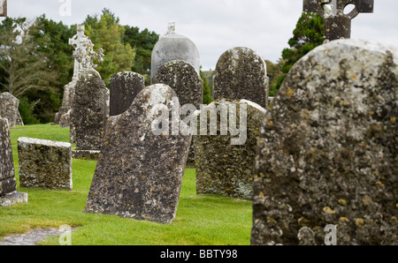 Vieux cimetière à Clonmacnoise. Pierres tombales couvertes de lichen incliné dans le cimetière qui entoure les églises à Clonmacnoise. Banque D'Images