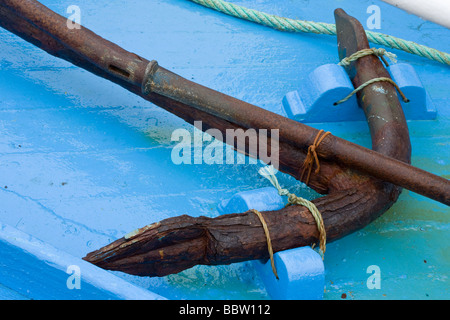 L'Ancre rouillée sur Bleu. Un très vieux fer rouillé anchor lié à la lame d'un bleu d'un petit bateau de pêche. Banque D'Images