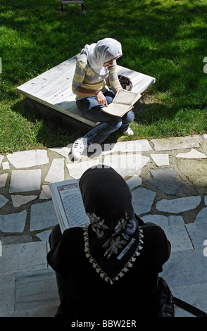 Deux femmes musulmanes voilées lire le Coran, jardin en face de la mosquée Sehzade Camii, Prince, Istanbul, Turquie Banque D'Images