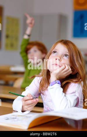 Les enfants dans une salle de classe en école primaire, girl daydreaming ou à pas sûr, pensif, triste ou frustré, l'égalité d'opportunité Banque D'Images