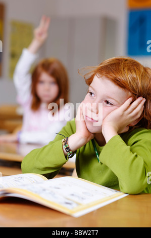 Les enfants dans une salle de classe à l'école primaire, rêvasser ou garçon à pas sûr, pensif, triste ou frustré, les garçons de devenir le Banque D'Images