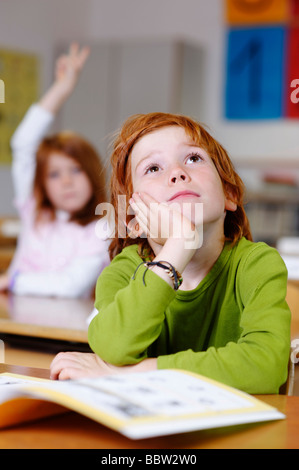 Les enfants dans une salle de classe à l'école primaire, rêvasser ou garçon à pas sûr, pensif, triste ou frustré, les garçons de devenir le Banque D'Images