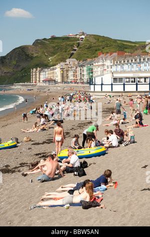 L'été des foules de jeunes étudiants se détendre et bronzer sur la plage de Galles Aberystwyth Royaume-uni à la fin de l'année scolaire Banque D'Images