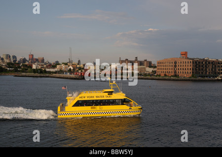 Un New York Water Taxi vitesse dans le port de New York sur son chemin de Manhattan à Brooklyn. Banque D'Images
