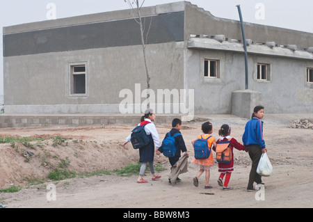 Les enfants de l'école à pied le long d'une route poussiéreuse quelque part à la périphérie de Pyongyang en Corée du Nord Banque D'Images