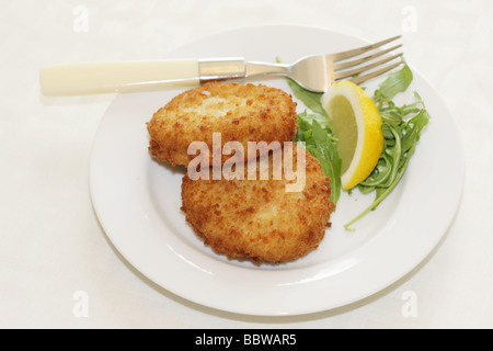 La morue panés délicieux fraîchement préparés Fishcakes avec citron et garnir de feuilles de salade isolé sur un fond blanc avec aucun peuple et un chemin de détourage Banque D'Images