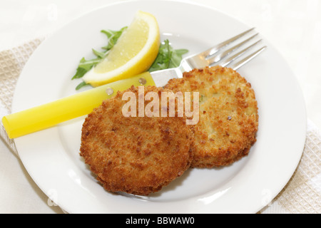 La morue panés délicieux fraîchement préparés Fishcakes avec citron et garnir de feuilles de salade isolé sur un fond blanc avec aucun peuple et un chemin de détourage Banque D'Images