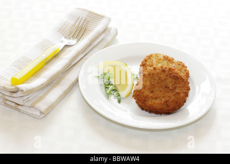 La morue panés délicieux fraîchement préparés Fishcakes avec citron et garnir de feuilles de salade isolé sur un fond blanc avec aucun peuple et un chemin de détourage Banque D'Images